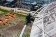 © chitsanupong - Male worker down height tank roof rope access safety inspection thickness weld of storage tank.