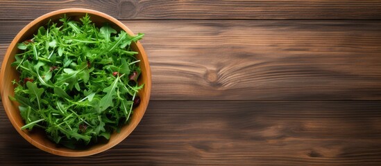 Wall Mural - A top down view of a wooden background featuring a bowl of fresh rucola salad with available copy space