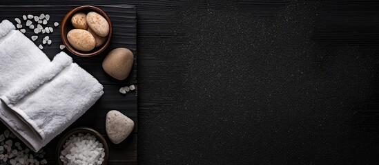Aufkleber - Top view of a spa set arrangement on a black background featuring sea salt a towel and a pumice stone for foot care The image provides ample copy space for text