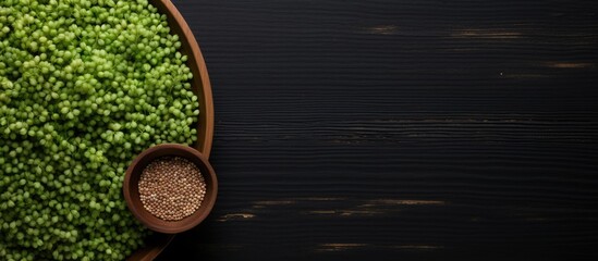 Wall Mural - Top view of raw green buckwheat on a black wooden background with plenty of copy space for an image