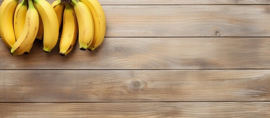Poster - A top view of three ripe bananas placed on a light wooden background leaving empty space for additional images or text