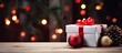 A white box adorned with a red ribbon and Christmas ball sits atop a vintage wooden surface surrounded by fir branches pine cones scissors and presents The background provides ample space for copy