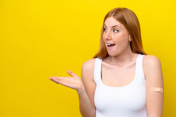 Wall Mural - Young redhead woman wearing a band-aids isolated on yellow background with surprise facial expression