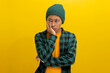 Bored young Asian man, in a beanie hat and casual outfit, rests his hand on his cheek, contemplating what to do, feeling bored, fatigued, and possibly a bit depressed. Isolated on yellow background.