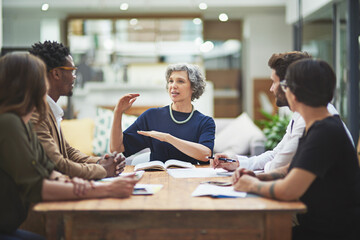 Wall Mural - Mature, woman and presentation for mentor, work and company in office for colleagues in business. Female professional, talking and coworkers in meeting for brainstorming, ideas and vision in startup