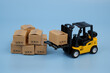 Forklift truck moving carton boxes on blue background. Copy space for text.