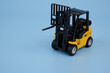 Yellow forklift truck on blue background, copy space for text.