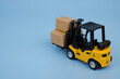 Forklift with carton boxes on blue background. Copy space for text.