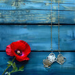 Memorial Day reflection with red poppy and dog tags on vintage blue wood.
