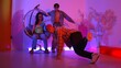 Happy hipster show break dancing while multicultural friend with casual cloth cheering at studio. Professional street dancer perform hip hop beat or lively rhyme with neon or led light. Regalement.
