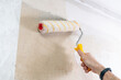 A man uses a roller to apply glue to a wall to paste wallpaper. Room renovation