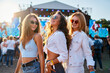 © artiemedvedev - Group of joyful girlfriends at beach festival, sunlit, dancing to live music, summer vibe, trendy outfits. Youth enjoying coastal event, fun moments, party atmosphere, sea backdrop.