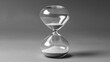 © RISHAD - Classic hourglass sits on a plain gray background, capturing the passage of time as sand slowly trickles from the top bulb to the bottom one.