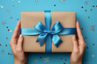 hands holding a gift box with blue ribbon and bow