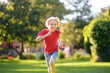 Elementary school child running on lawn in urban park on sunny day. Happy preteen boy having fun during walk. Outdoors activity for kids on summer holidays