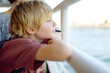Cute blonde preteen tourist boy is traveling by boat or ferry on the sea. Family vacations on ocean or sea. Summer leisure for families with kids.