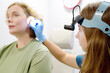 A patient is seen by an otolaryngologist. A professional ENT doctor examines a patient. An otolaryngologist examines a patient's inner ear using an otoscope