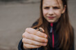 A small beautiful girl, a teenage child, looks with interest, curiosity at a caught cockchafer, a large insect, a beetle on her arm, palm outdoors in nature. Animal photography.