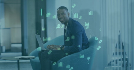 Poster - Image of graphs and financial icons over african american businessman using laptop on armchair