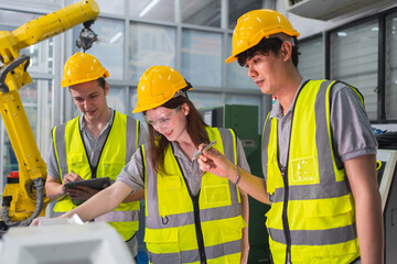 Wall Mural - A Group of engineer are examining machine robot arm with smart tablet. Installation indoor industrial factory. Technician coworker check for repair maintenance electronic operation with remote system