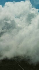 Wall Mural - Flying through beautiful white fluffy clouds in blue sky. Airplane travel background. Vertical video