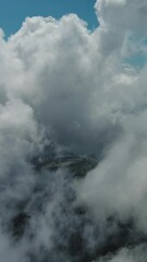 Wall Mural - Flying through beautiful white fluffy clouds in blue sky. Airplane travel background. Vertical video