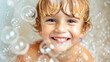 © Anna - Excited young child grins widely surrounded by soap bubbles in the bath