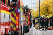 Red fire trucks in row. Teams of fire brigade on city street. Selective focus on blue flasher.