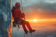 © Iryna - A climber in a safety helmet, hanging from ropes on a skyscraper during sunset.