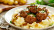 Delicious swedish meatballs and creamy mashed potatoes, topped with parsley and rich gravy, presented on a white platter