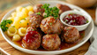 Traditional swedish meatballs served with creamy lingonberry sauce, parsley, and boiled potatoes on a white plate, scandinavian cuisine