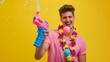 Young smiling fun man 20s he wear pink tshirt hawaiian lei near hotel pool hold in hand inflatable ball play shoot from water gun isolated on plain yellow background Summer vacation se : Generative AI