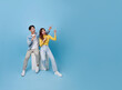 Happy Asian couple sitting on white cube chair and presenting or showing hand pointing finger with for product isolated on blue studio copy space background.
