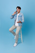 Portrait happy smiling young asian man using smartphone sitting on chair isolated on blue background. People And Technology Concept.