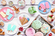 Cool summer food table scene. Variety of ice cream, popsicles and frozen treats. Pastel colors. Above view on a white wood background.