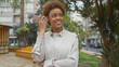 © Krakenimages.com - Smiling african american woman using smartphone outdoors in city park