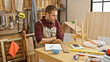 © Krakenimages.com - Handsome hispanic man in apron contemplating a wooden model in a well-equipped carpentry workshop.