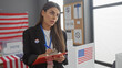 © Krakenimages.com - Hispanic woman taking notes at an american electoral college polling station, adorned with flags.