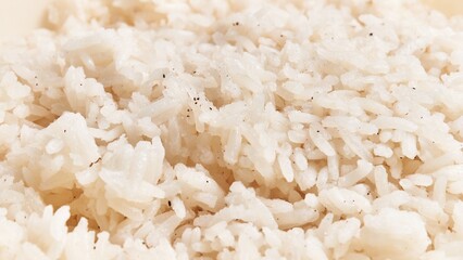 Wall Mural - Close-up of cooked white basmati rice grains with visible seasoning specks on a plain background.