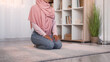Religious muslim. Islam worship. Allah faith. Unrecognizable woman in hijab clothes praying on floor at home interior with free space.