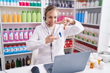 Canvas Print - Young caucasian woman working at pharmacy drugstore using laptop smiling making frame with hands and fingers with happy face. creativity and photography concept.