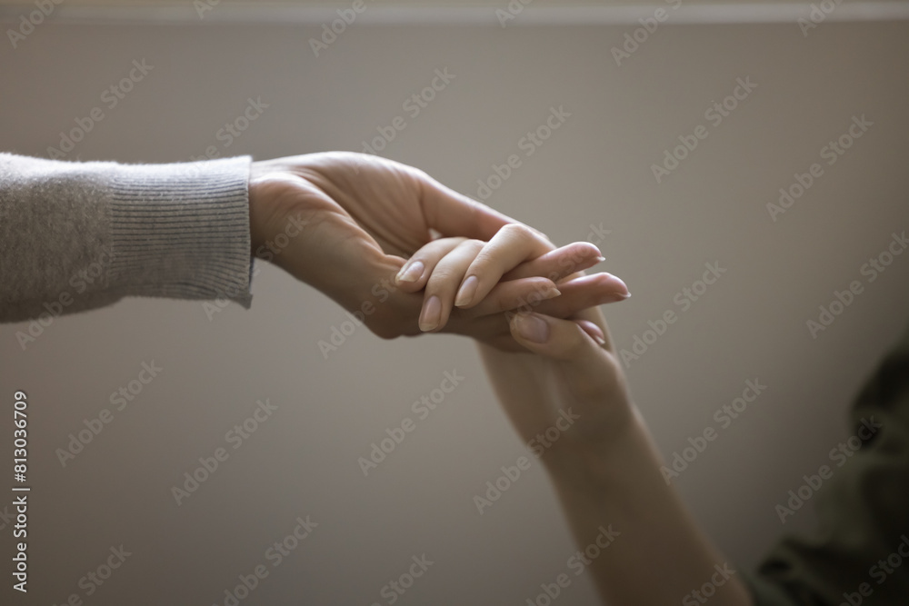 Woman and teenager girl holding hands close up cropped shot. Adult ...
