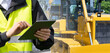 Worker in a helmet with a digital tablet on the background of construction machine..