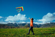 Happy boy with kite on green field on mountains background