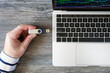 © SKfoto GE - Top view of a man inserting a flash drive into a laptop on a wooden table.