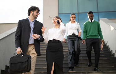 A dynamic image of business professionals in smart attire descending outdoor stairs, engaged in conversation.