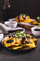 Canvas Print - Mexican nacho chips baked with chicken, black beans and cheese on a plate vertical view