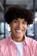In modern office, biracial young male coworker wearing striped shirt, smiling