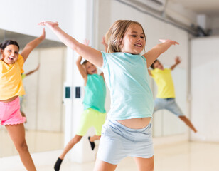 Wall Mural - Young girls and boys jumping together in dance studio.