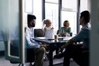 © Wavebreak Media - Diverse team gathering around table with a laptop at office